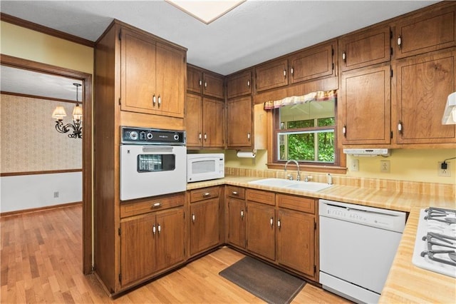 3802 SW Knights Bridge Rd SW, Lilburn, GA 30047 - kitchen with white appliances, a sink, light countertops, light wood-style flooring, and ornamental molding
