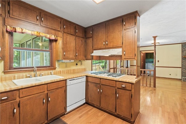3802 SW Knights Bridge Rd SW, Lilburn, GA 30047 - kitchen with white appliances, a sink, under cabinet range hood, brown cabinets, and light wood-style flooring
