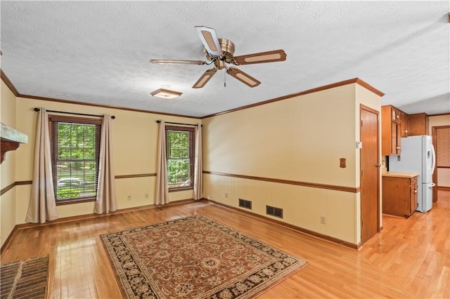 3802 SW Knights Bridge Rd SW, Lilburn, GA 30047 - spare room featuring light wood-style flooring, healthy amount of natural light, a ceiling fan, a textured ceiling, and ornamental molding