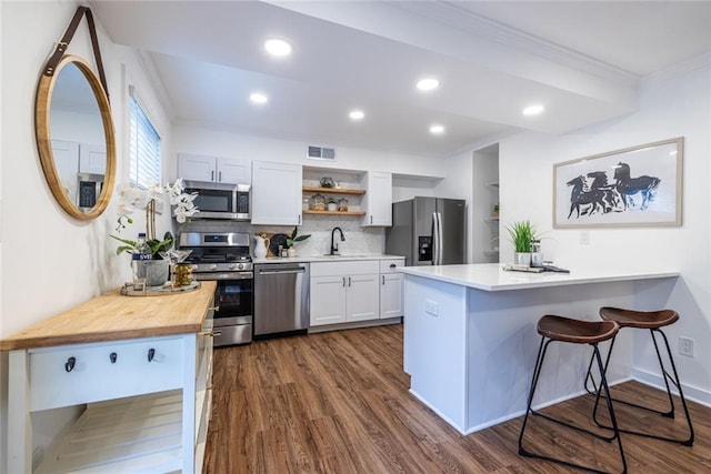 115 Biscayne Dr NW Unit F10, Atlanta, GA 30309 - kitchen with stainless steel appliances, open shelves, a sink, crown molding, and dark wood-type flooring