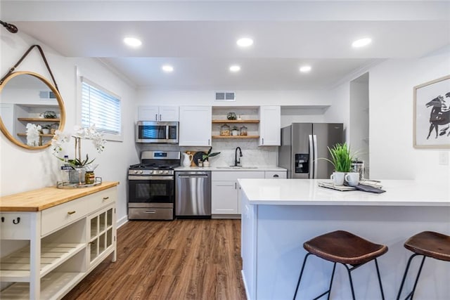 115 Biscayne Dr NW Unit F10, Atlanta, GA 30309 - kitchen featuring appliances with stainless steel finishes, open shelves, a breakfast bar, dark wood finished floors, and tasteful backsplash