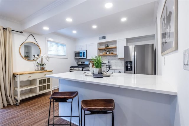 115 Biscayne Dr NW Unit F10, Atlanta, GA 30309 - kitchen featuring stainless steel appliances, ornamental molding, open shelves, a peninsula, and a breakfast bar