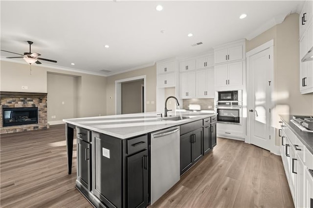 kitchen featuring a sink, white cabinetry, dark cabinetry, appliances with stainless steel finishes, and crown molding