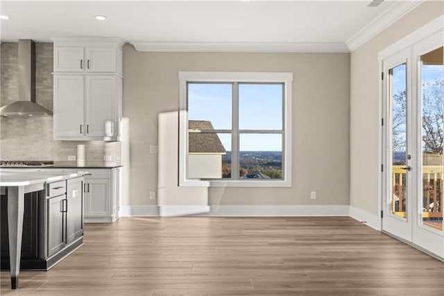 kitchen featuring wall chimney range hood, tasteful backsplash, ornamental molding, and french doors