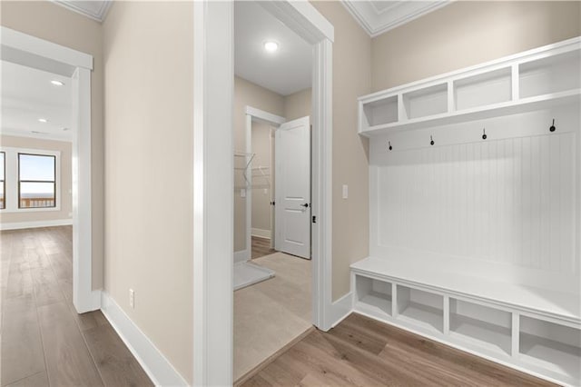 mudroom featuring crown molding, baseboards, and wood finished floors