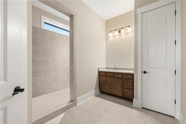 bathroom featuring a walk in shower, tile patterned flooring, vanity, and baseboards