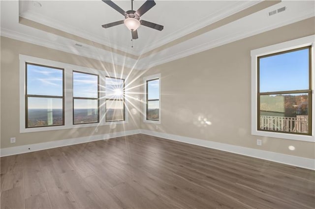 unfurnished room with dark wood-style floors, a raised ceiling, visible vents, ornamental molding, and baseboards