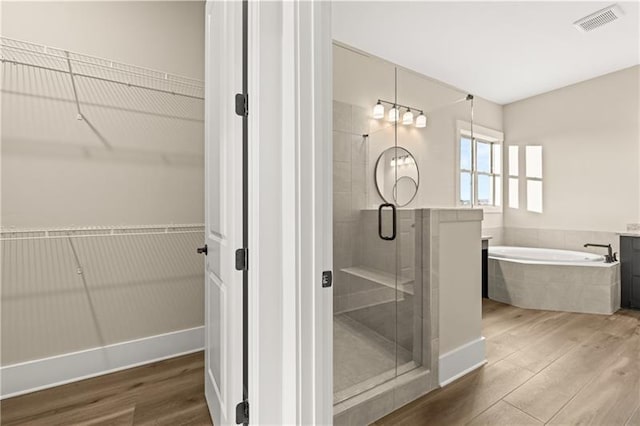 full bath with a garden tub, a shower stall, visible vents, and wood finished floors