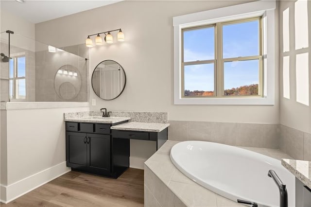 bathroom featuring wood finished floors, vanity, baseboards, a bath, and walk in shower