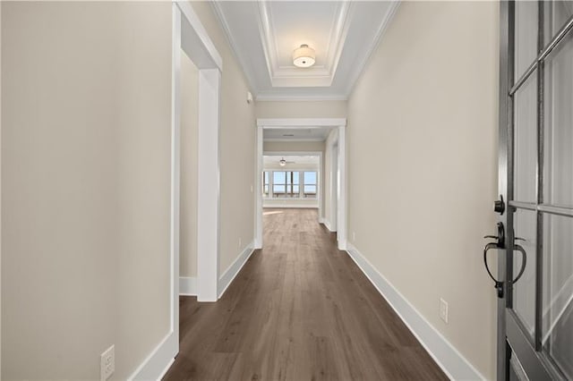 hall with dark wood-style floors, a tray ceiling, crown molding, and baseboards