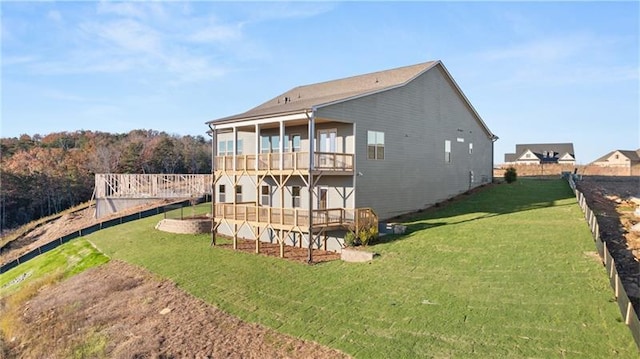 back of house featuring fence, a deck, and a lawn