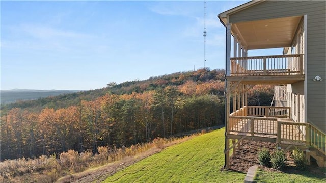 view of yard with a deck, stairway, and a wooded view