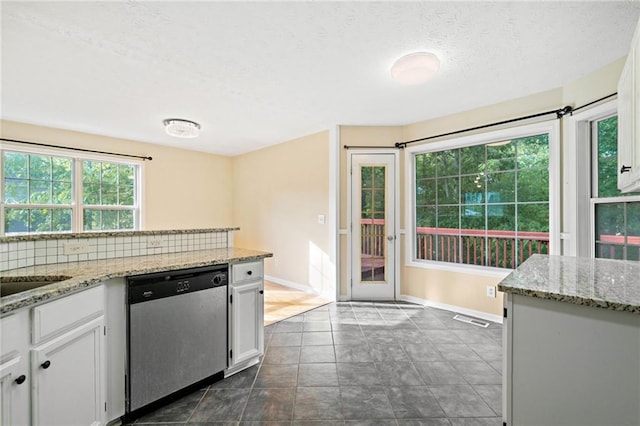 kitchen featuring stainless steel dishwasher, a textured ceiling, baseboards, and white cabinetry