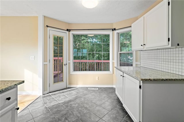 entryway featuring baseboards, tile patterned flooring, a textured ceiling, and visible vents