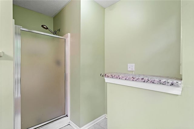 full bath with a textured ceiling, baseboards, tile patterned floors, and a stall shower