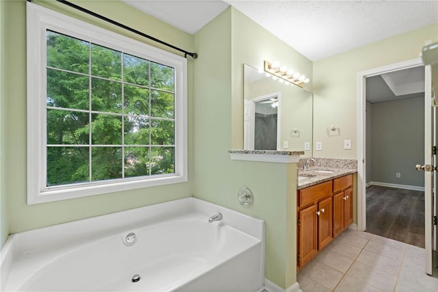 bathroom with a healthy amount of sunlight, tile patterned floors, vanity, and a garden tub
