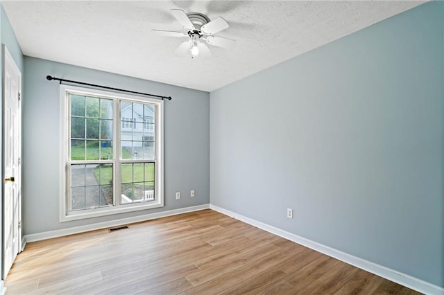 unfurnished room featuring light wood-style floors, a textured ceiling, a ceiling fan, baseboards, and visible vents