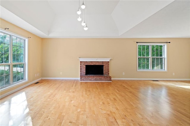 unfurnished living room with track lighting, lofted ceiling, light wood-style flooring, and a wealth of natural light