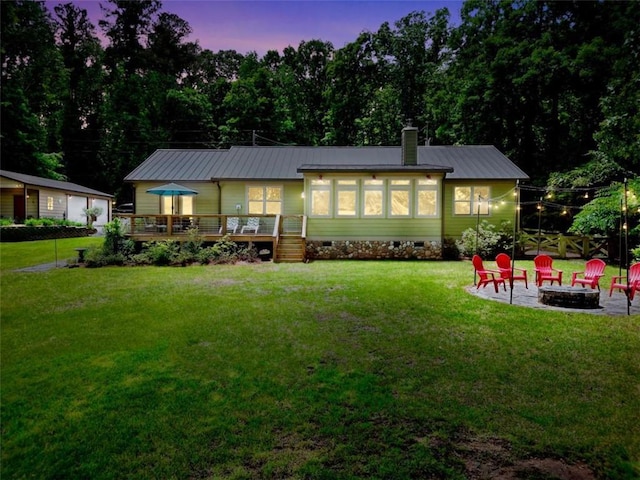 184 Bradley Rd, Jackson, GA 30233 - back of property at dusk with an outdoor fire pit, crawl space, a wooden deck, a lawn, and metal roof