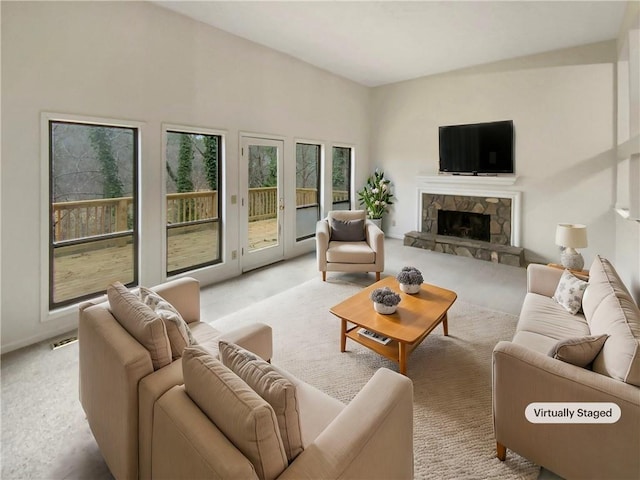 carpeted living room featuring a stone fireplace