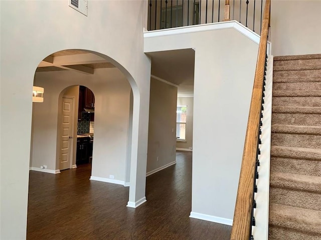 stairway featuring wood-type flooring and beamed ceiling