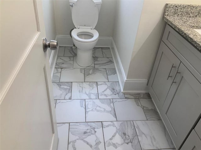 bathroom featuring vanity, toilet, baseboards, and marble finish floor