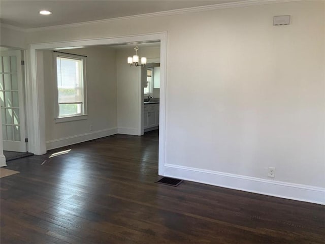 unfurnished dining area featuring baseboards, dark wood finished floors, a sink, ornamental molding, and a chandelier