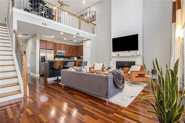 6023 Brookside Oak Cir, Norcross, GA 30093 - living room with a towering ceiling, stairs, dark wood-style floors, a warm lit fireplace, and baseboards