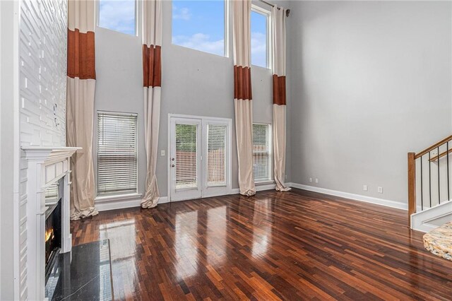 6023 Brookside Oak Cir, Norcross, GA 30093 - unfurnished living room with stairs, a towering ceiling, a warm lit fireplace, baseboards, and wood finished floors