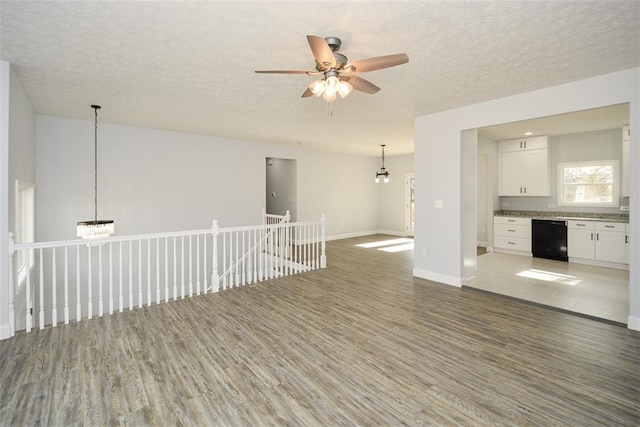 spare room with hardwood / wood-style flooring, ceiling fan with notable chandelier, and a textured ceiling