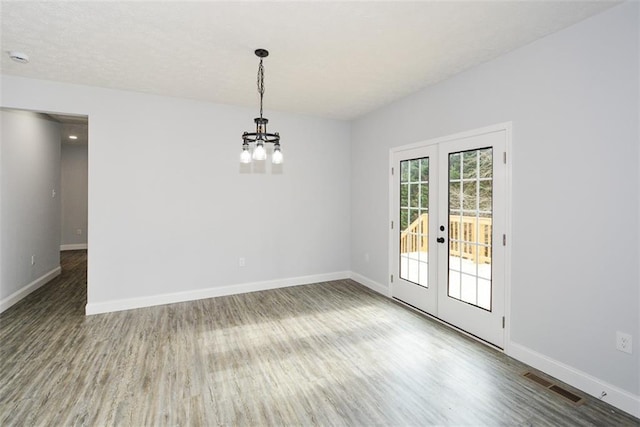 spare room featuring hardwood / wood-style floors, a notable chandelier, and french doors