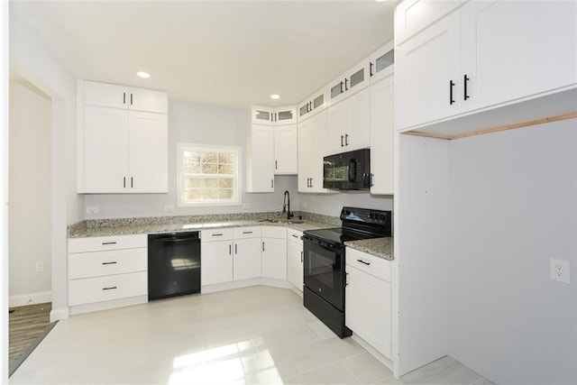 kitchen with white cabinetry, sink, light stone counters, and black appliances