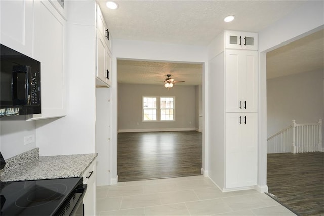 kitchen featuring black appliances, white cabinetry, light tile patterned floors, ceiling fan, and light stone counters