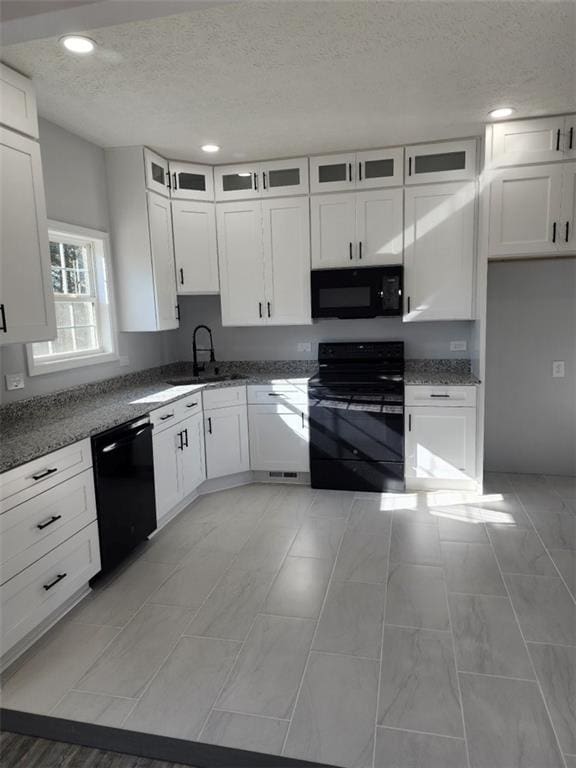 kitchen with a textured ceiling, sink, white cabinets, and black appliances