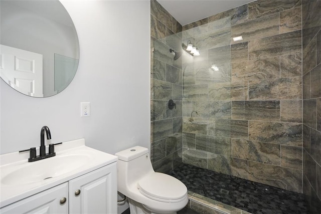 bathroom with vanity, a tile shower, and toilet