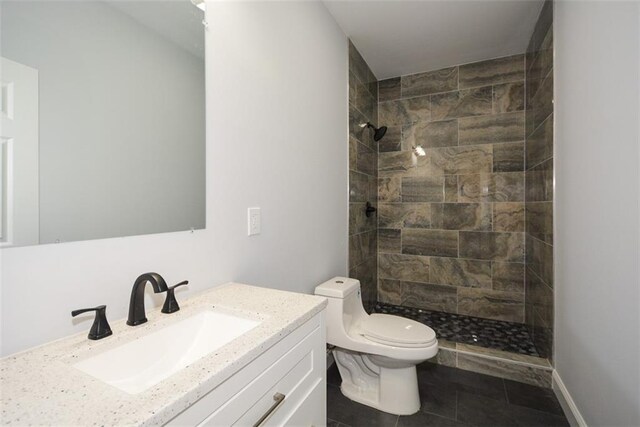 bathroom featuring vanity, toilet, and tiled shower