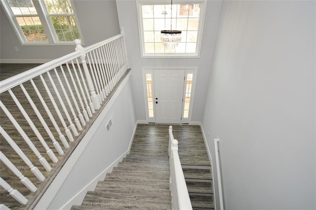 foyer featuring a high ceiling, plenty of natural light, a notable chandelier, and dark hardwood / wood-style flooring