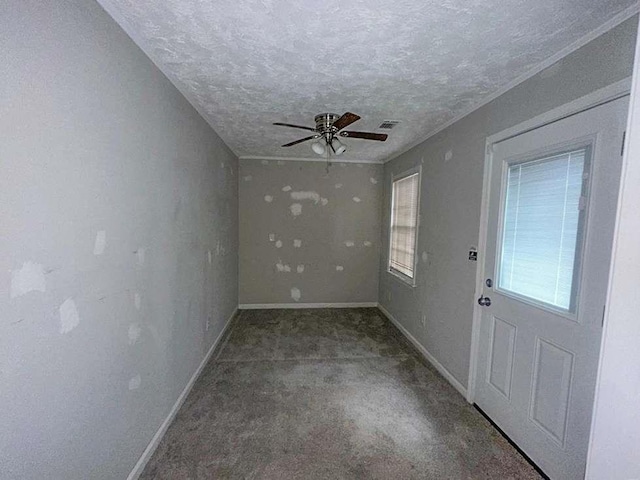 carpeted empty room featuring a ceiling fan, visible vents, a textured ceiling, and baseboards