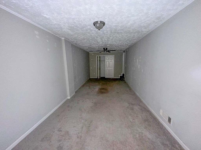 corridor with a textured ceiling, visible vents, carpet, and baseboards