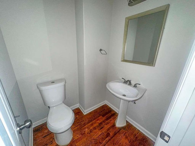 bathroom with baseboards, wood finished floors, and toilet