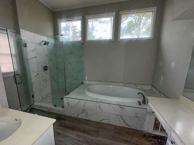 bathroom featuring wood finished floors, vanity, a bath, and a marble finish shower