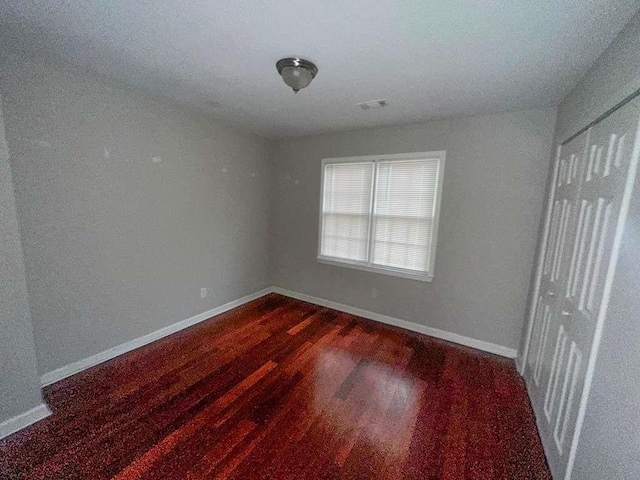 unfurnished bedroom featuring dark wood finished floors and baseboards