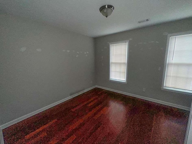 unfurnished room with baseboards, visible vents, and a wealth of natural light