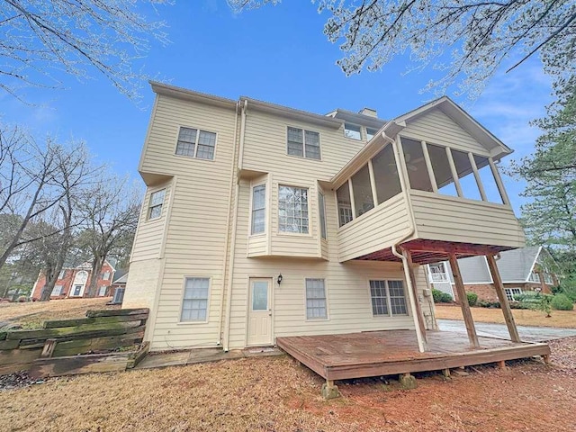 back of house featuring a sunroom, a deck, and a chimney