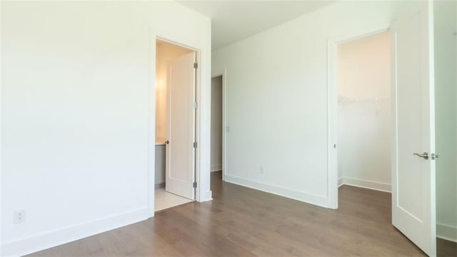 7020 Cottage Grove Dr, Flowery Branch, GA 30542 - unfurnished bedroom featuring wood finished floors, a closet, and a walk in closet