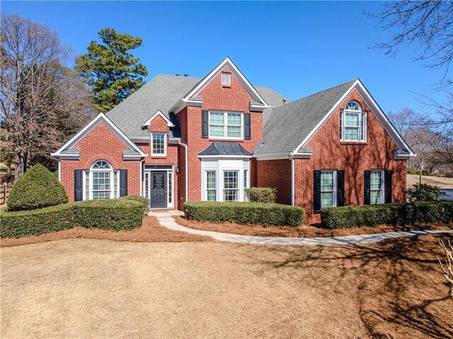 traditional-style house with brick siding and a shingled roof
