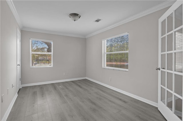 empty room with wood finished floors, baseboards, ornamental molding, and visible vents