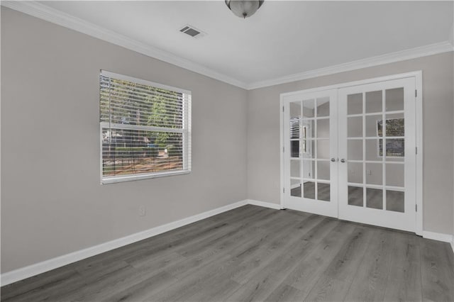 spare room with crown molding, visible vents, wood finished floors, french doors, and baseboards