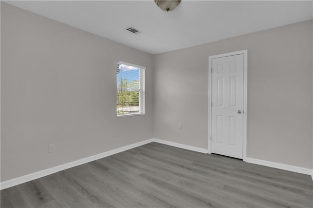 unfurnished room with dark wood-type flooring, visible vents, and baseboards