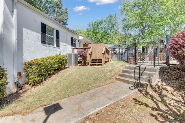 view of yard featuring central AC, fence, and a wooden deck